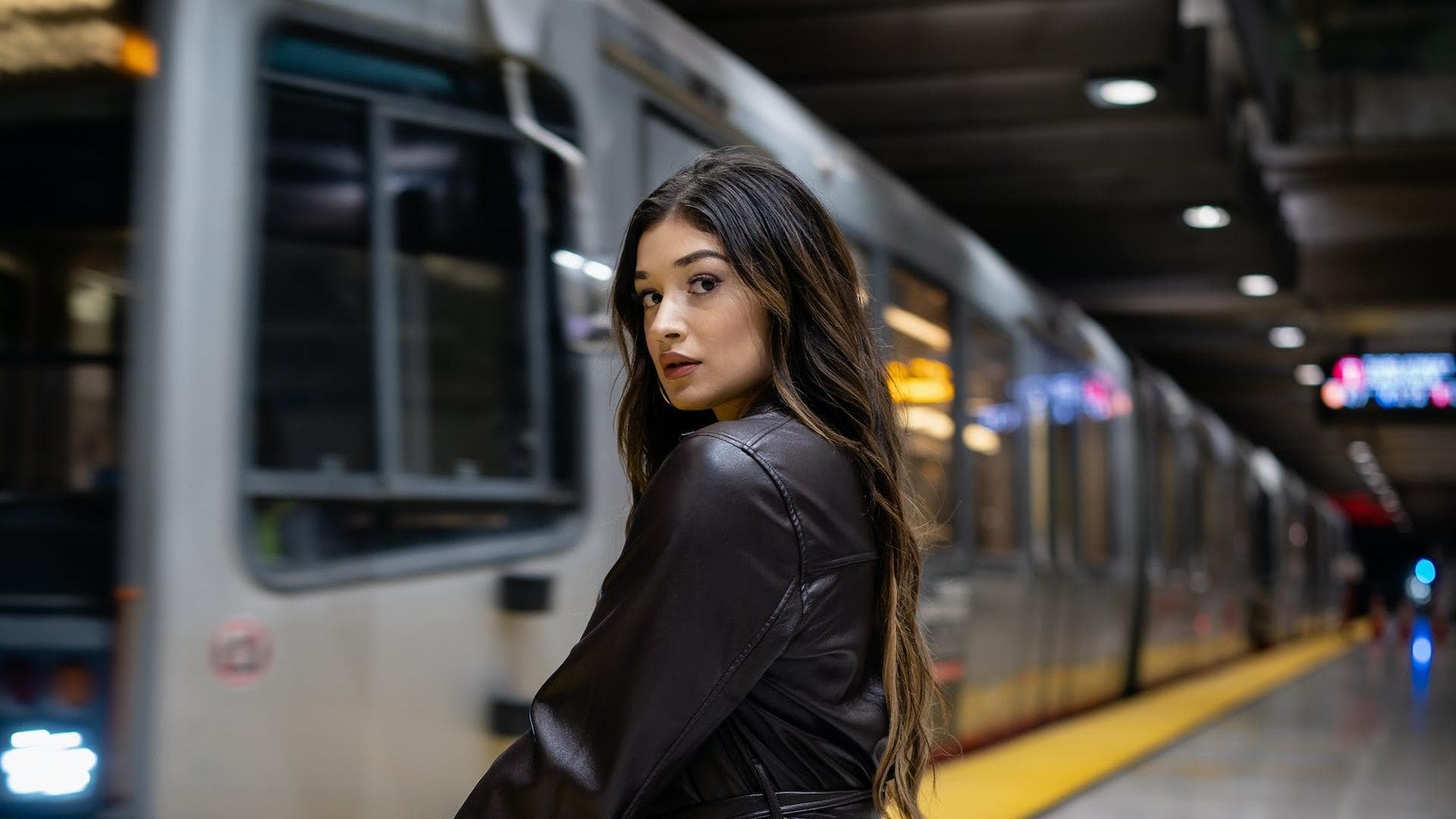 Frau im Ledermantel vor der U-Bahn.