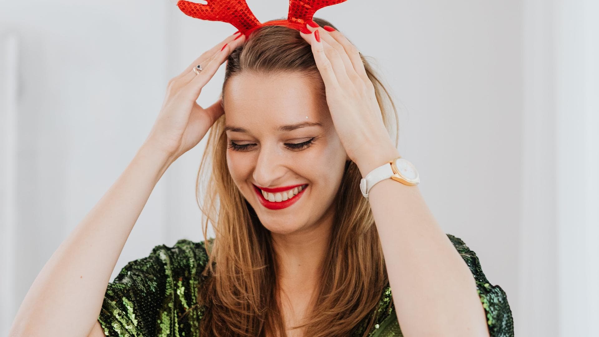 Frau im grünen Pailettenkleid und roten Haarreifen