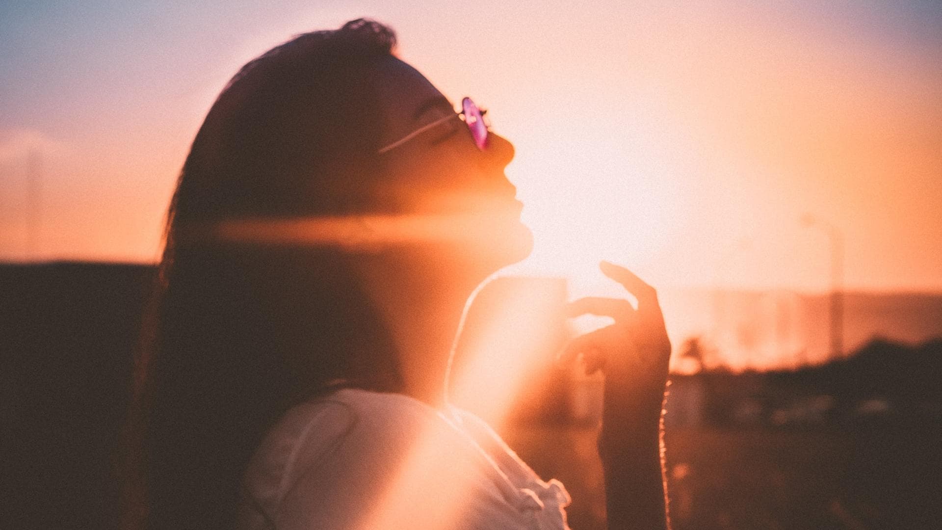 Frau mit langen Haaren und Brille beim Sonnenuntergang