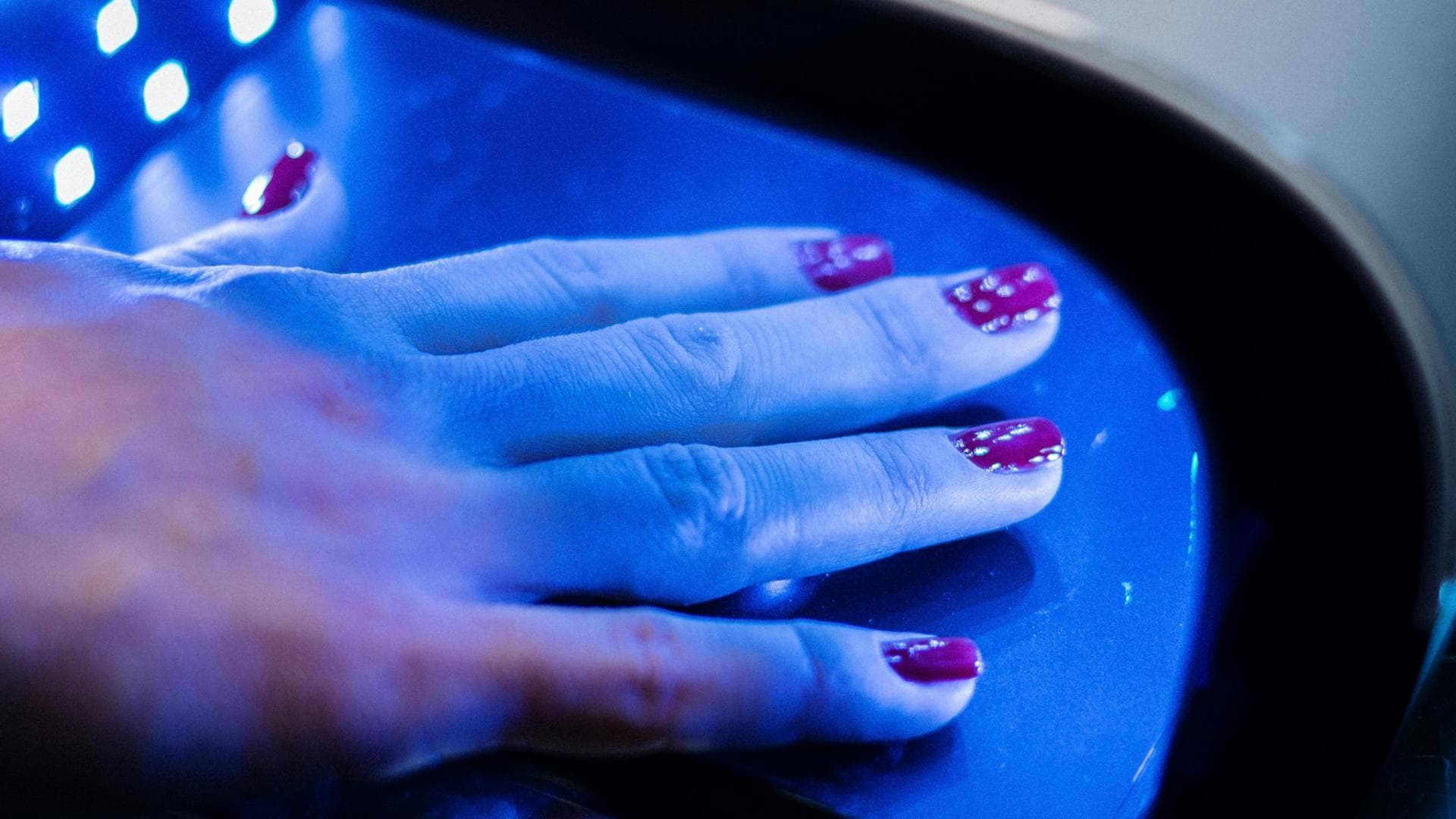 Weibliche Hand mit Nagellack unter UV-Lampe