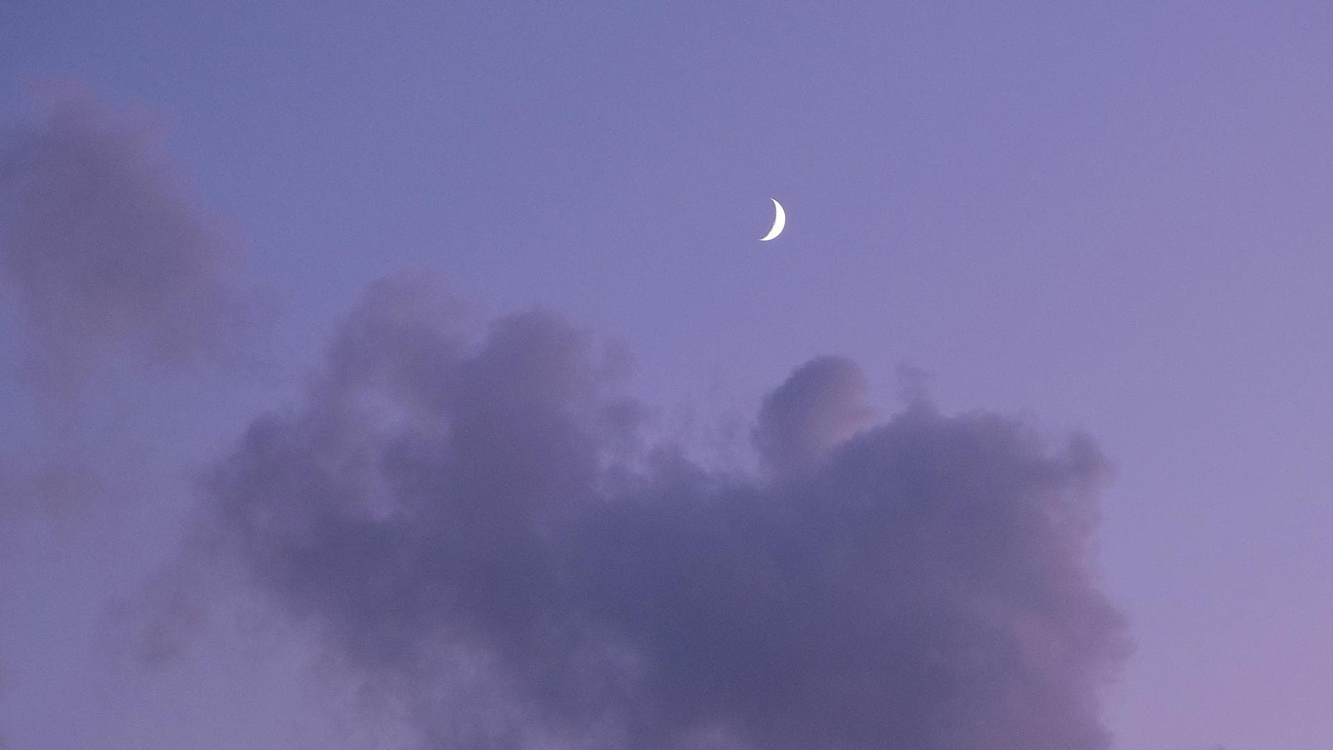 Halbmond am lilafarbenen Himmel mit Wolken