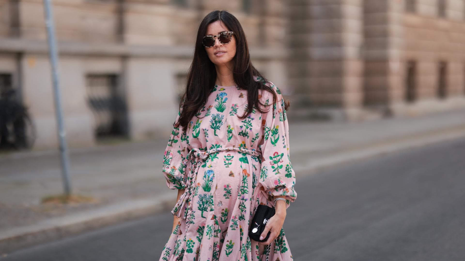 Schwangere Frau im rosanen Kleid mit Sonnenbrille