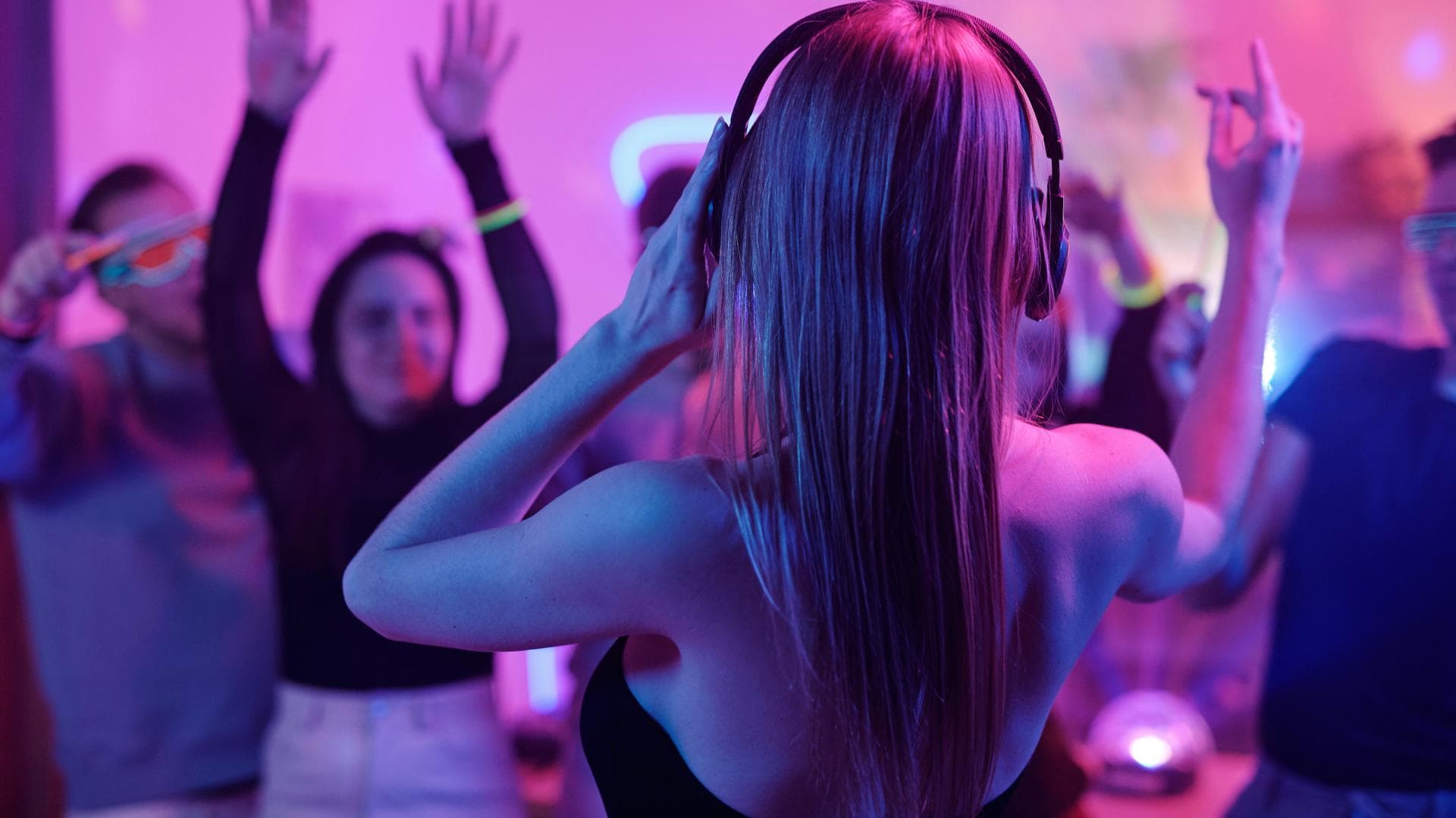 Frau mit Kopfhörern feiert mit anderen Leuten