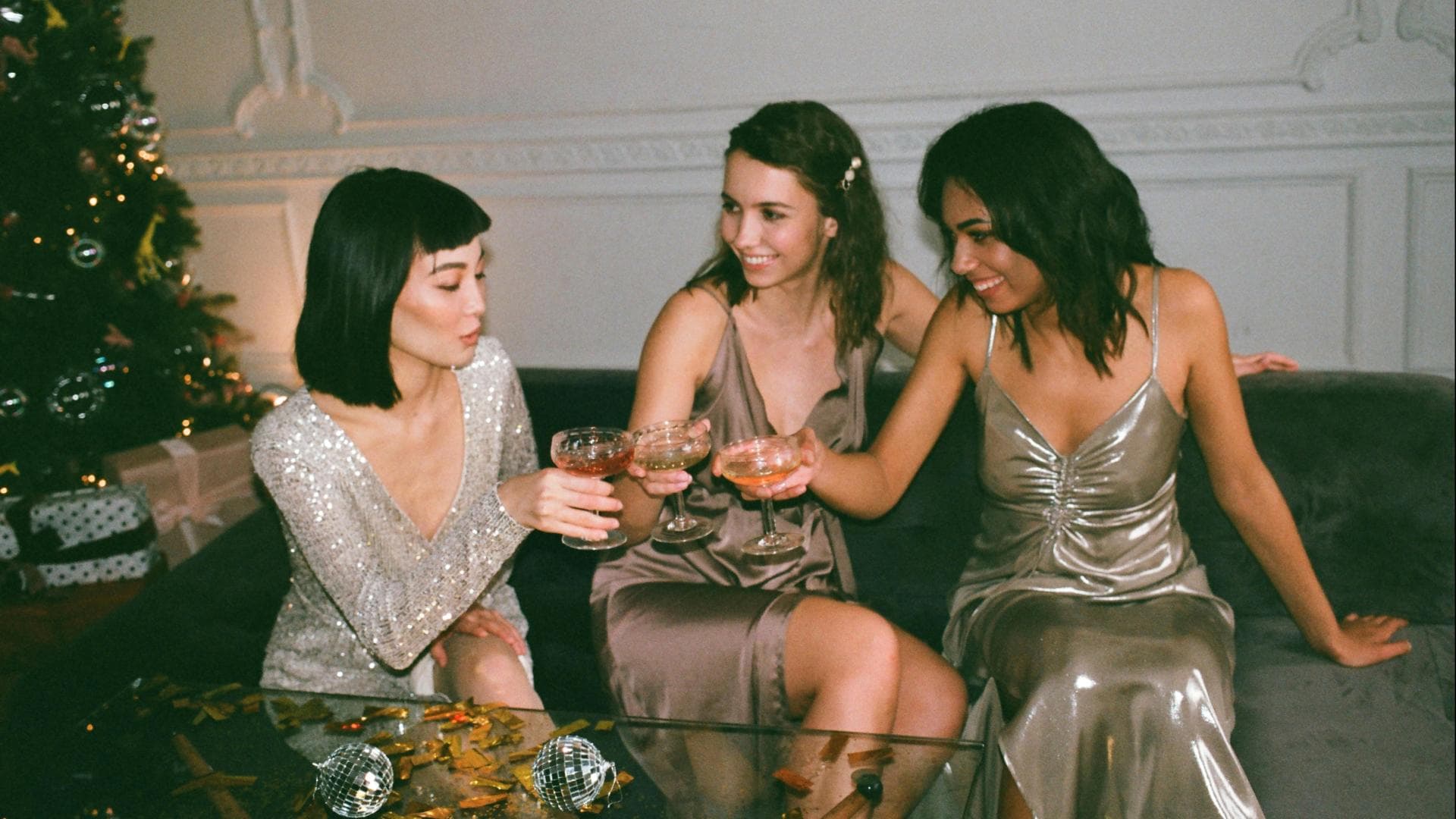 Drei Frauen stoßen mit festlichen Drinks an