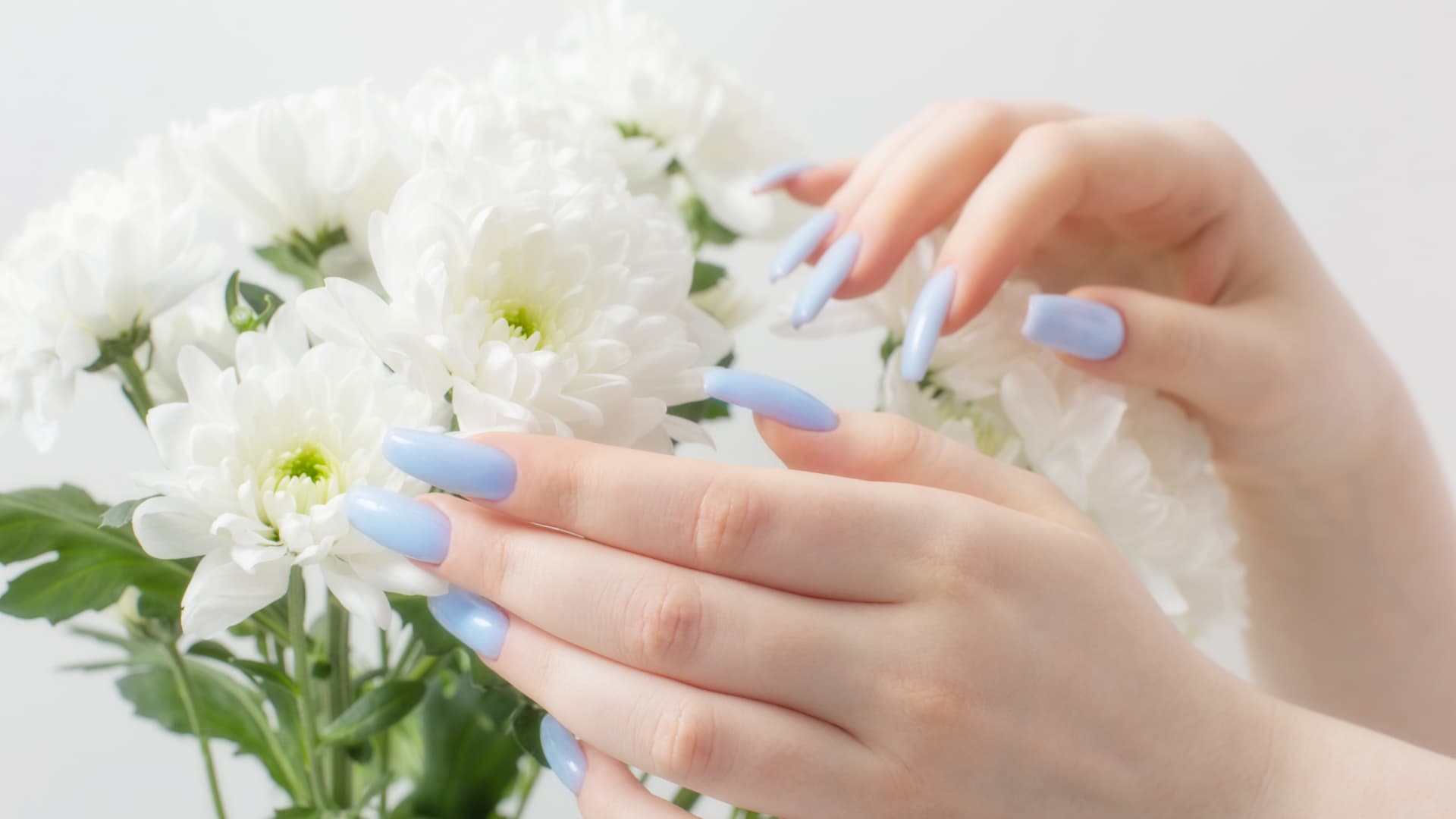Hände mit hellblauen Nägeln und weiße Blumen
