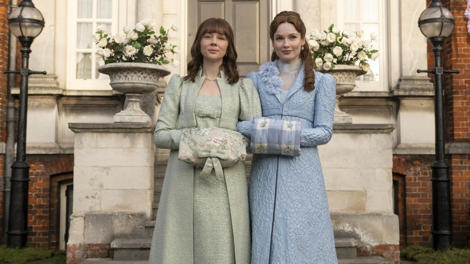 Zwei Frauen mit langen, eleganten Kleidern vor einem Schloss.