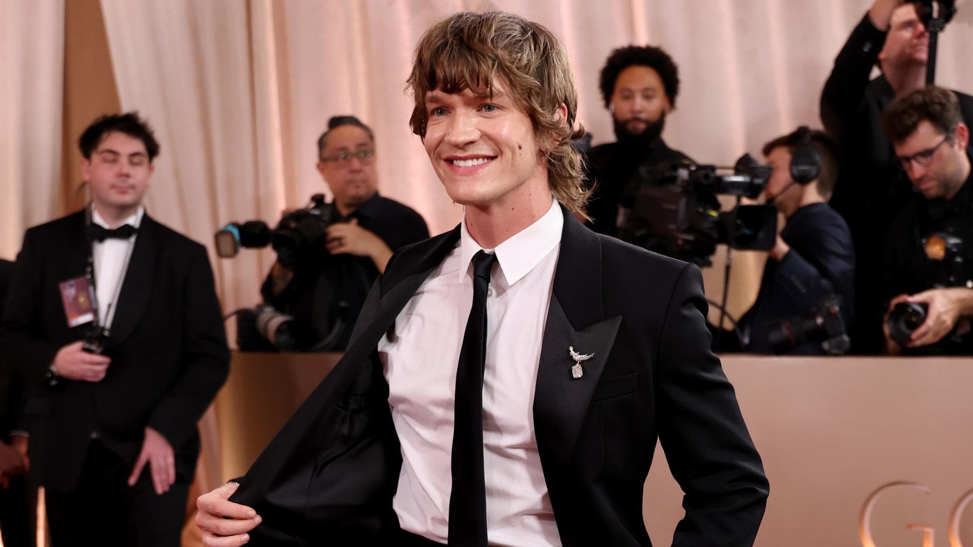 Connor Storrie in einem schwarzen Anzug auf dem Roten Teppich.