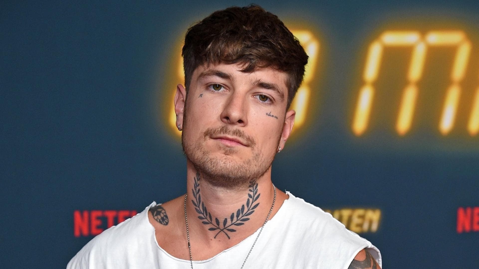 Willi Banner mit einem weißen Tanktop, einer Kette und voll tattoowierten Armen.