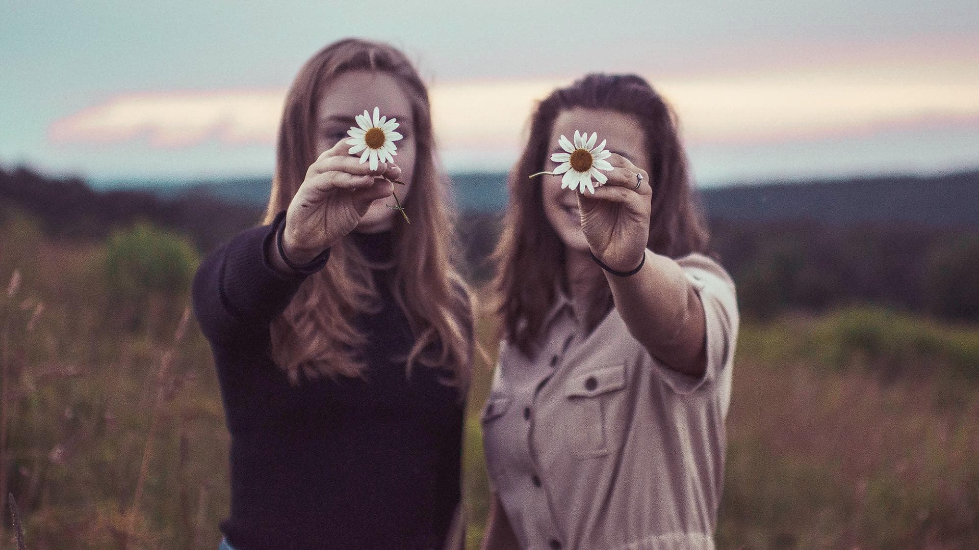 Zwei Frauen halten Blumen vor ihr Gesicht