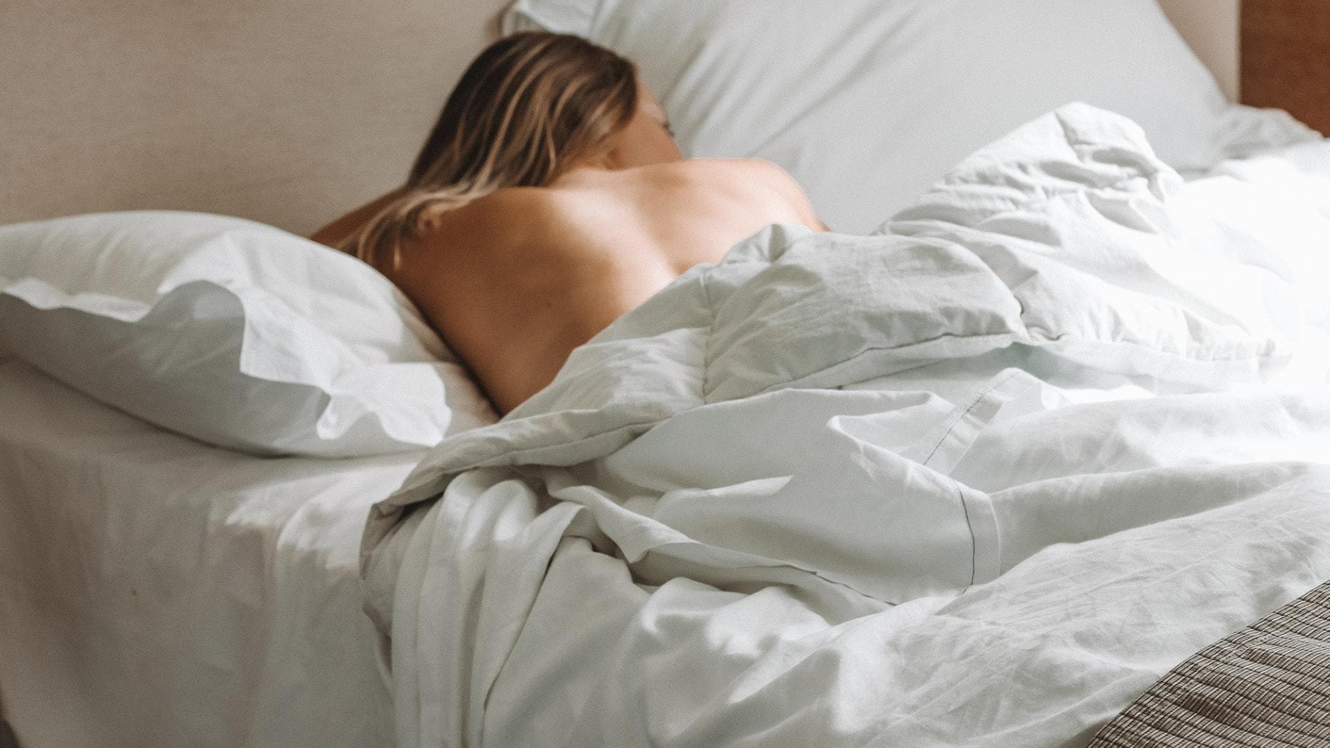 Frau liegt unbekleidet im Bett