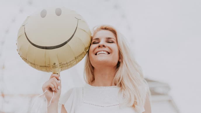 Horoskop: Frau lacht mit Luftballon