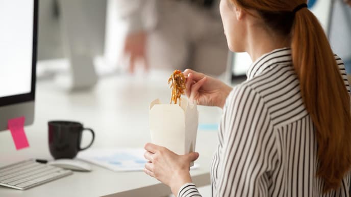 Schreibtisch-Diät: Frau ist Mittag am Schreibtisch