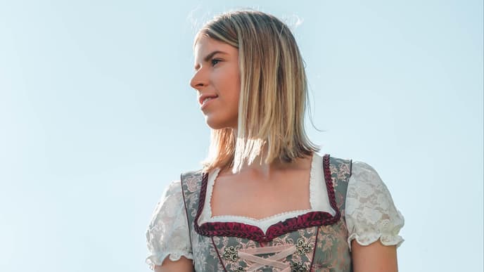 Frau in einem grün-roten Dirndl mit dezentem Dekolleté
