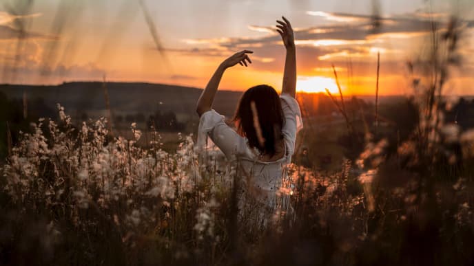 Horoskop Thema: Frau die im Feld steht und die Arme in die Luft streckt