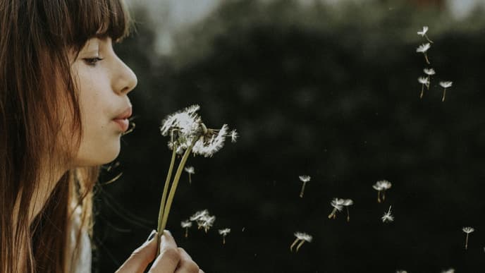 Frau pustet Pusteblume
