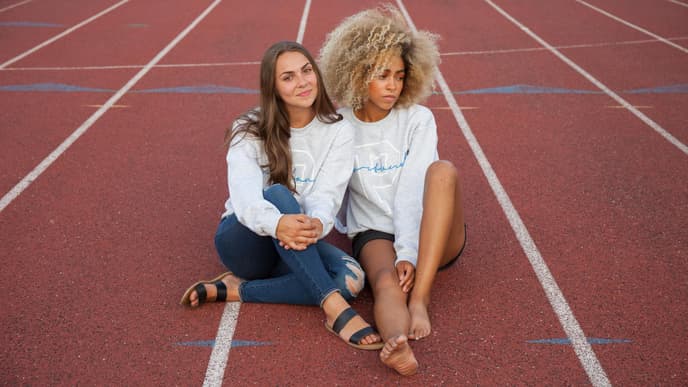 Frauen sitzen auf Sportplatz