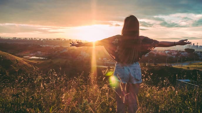Horoskop Thema: Frau steht auf Berg bei Sonnenuntergang