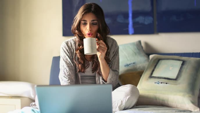 frau im bett mit kaffee und laptop