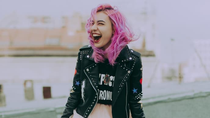 Horoskop: Frau lacht mit rosa Haaren