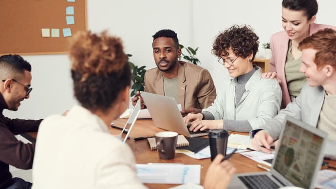 Frauen und Männer sitzen am Arbeits-Tisch