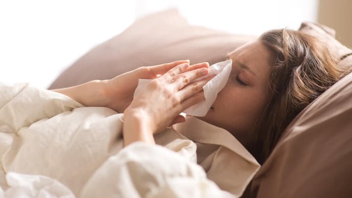 Frau liegt krank im Bett