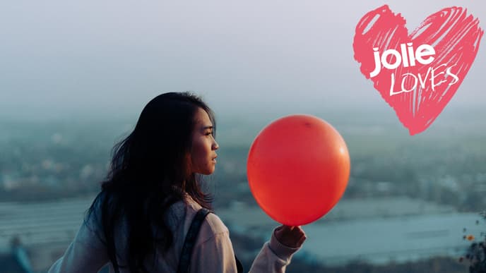 Frau hält roten Luftballon in der Hand