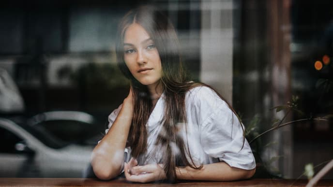 Frau sitzt hinter Fensterscheibe