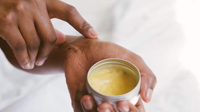 Frau hält Body Butter in den Händen