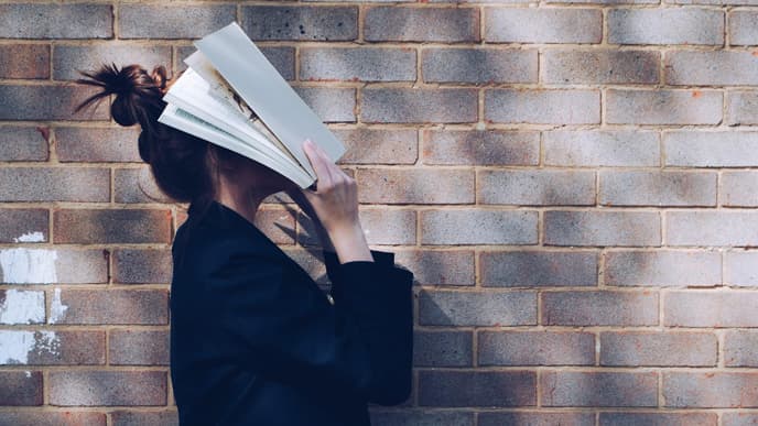 Frau schlägt sich ein Buch über den Kopf