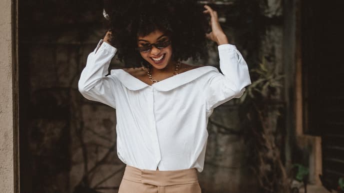 Horoskop: Frau mit Afro und Sonnenbrille lacht 