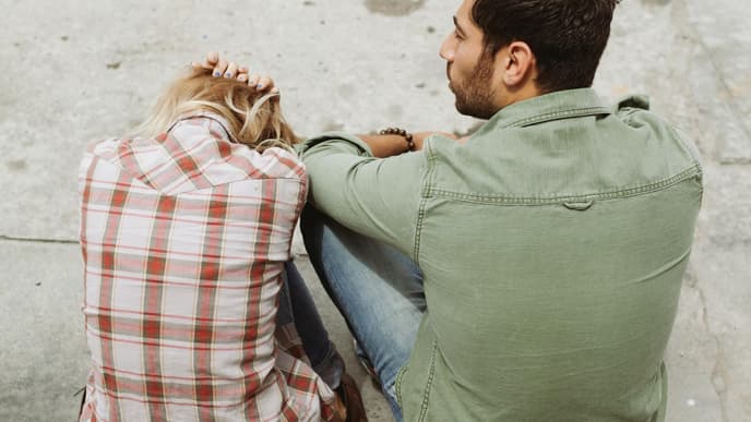 Frau und Mann sitzen mit dem Rücken zur Kamera