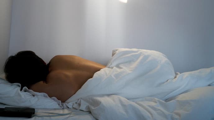 Rücken einer Frau die im Bett liegt