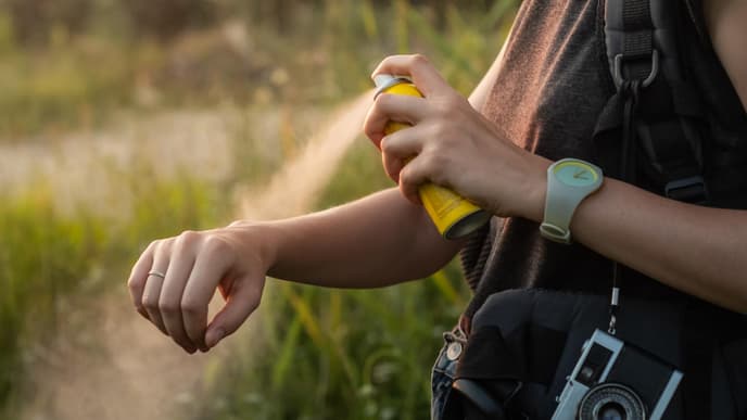 Frau sprüht Spray gegen Mückenstiche