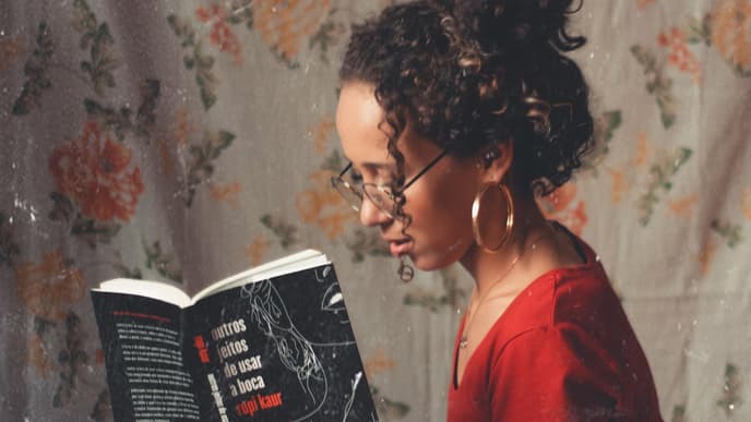 Mädchen mit Buch und Tasse in den Händen vor geblümter Wand