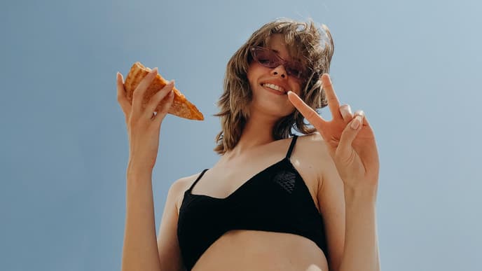 Frau mit einem Pizza Stück in der Hand