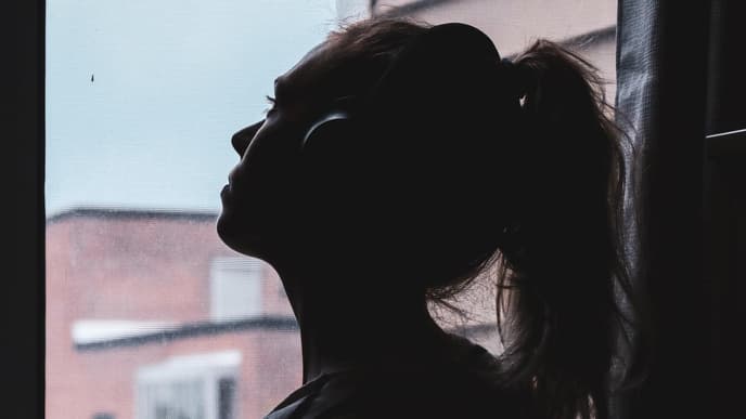 Frau am offenen Fenster mit Kopfhörern