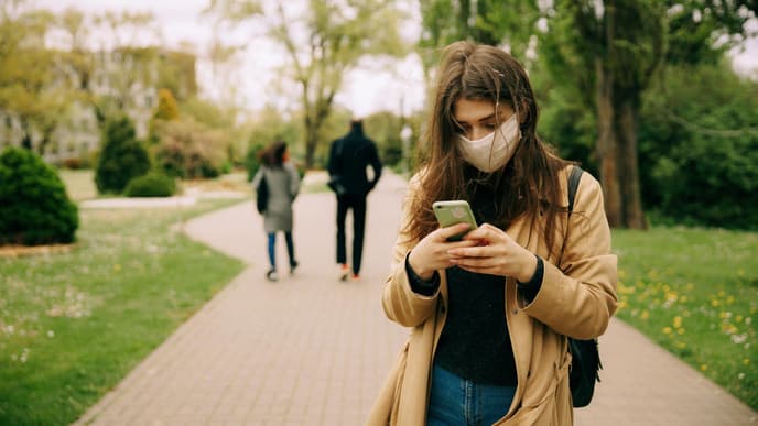 Frau mit Handy und Mundschutz