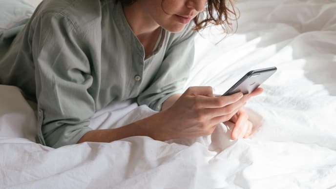 Frau auf einem Bett mit Handy