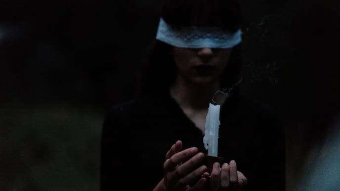 Mädchen mit verbundenen Augen und Kerze in der Hand