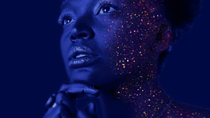 Frau mit Glitzerpartikel im Gesicht im Schwarzlicht