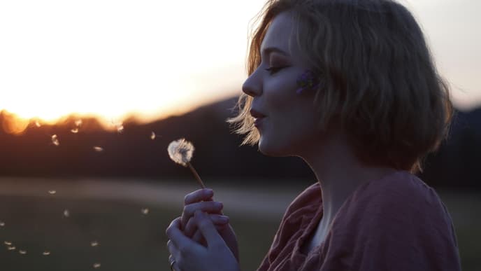 Frau pustet Pusteblume
