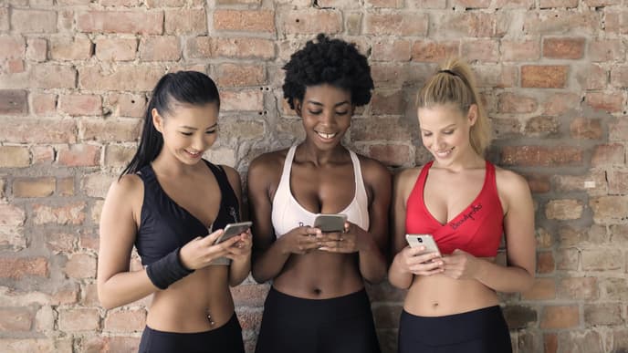 Frauen in Sport-Outfit mit Handy in der Hand