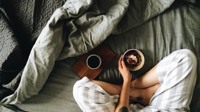 Frau sitzt mit Frühstück im Bett