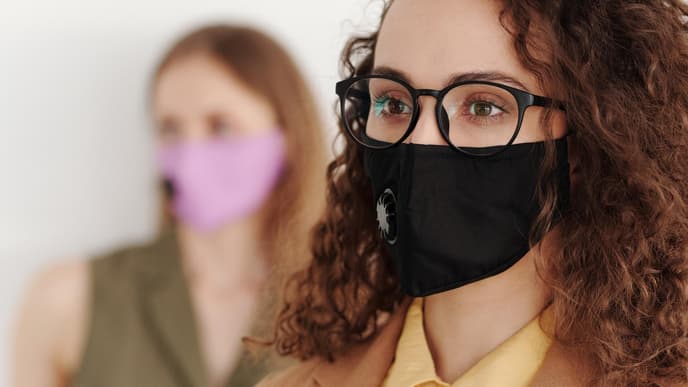 Frau mit schwarzer Brille und Mundschutz
