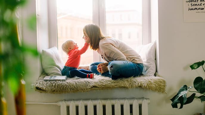 Baby haelt Gesicht von jungen Frau
