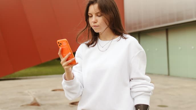 Date Nachrichten: Frau mit Armprothese und Handy in der Hand
