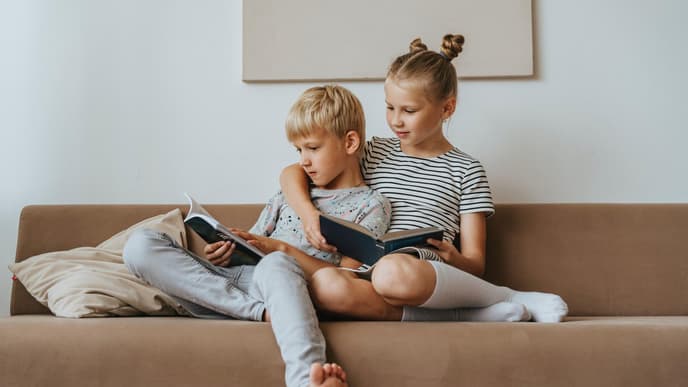 Große Schwester mit kleinem Bruder im Arm auf der Couch