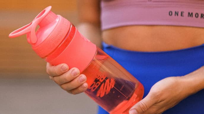 Frau im Sport-Outfit hält Flasche