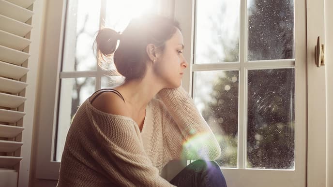 Frau schaut traurig aus dem Fenster