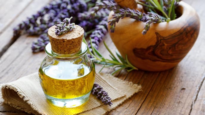 Lavendelöl in einer Flasche auf einem Holztisch mit Lavendelblüten